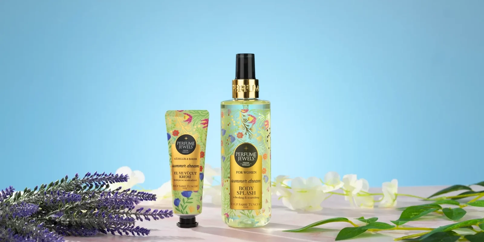 Pastel mavi arkada lavanta ve yapraklarla çerçevelenmiş çiçek desenli vücut spreyi ve el kremi, detay odaklı ürün çekimi.