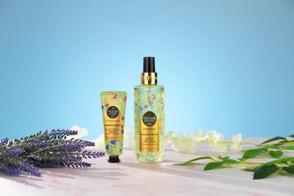 Pastel mavi arkada lavanta ve yapraklarla çerçevelenmiş çiçek desenli vücut spreyi ve el kremi, detay odaklı ürün çekimi.