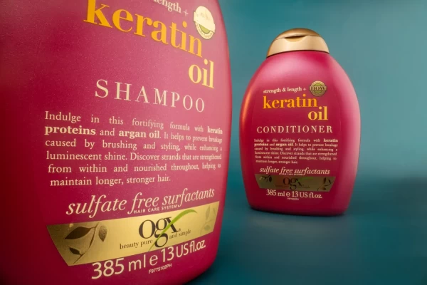 Mavi zeminde parlak pembe keratin oil şişeleri yakın plan, detay odaklı ürün çekimi ve stüdyo çekimi.