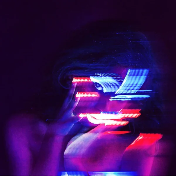 Creative editorial portrait shot focusing on a half-hidden face with neon blue and pink light beams.