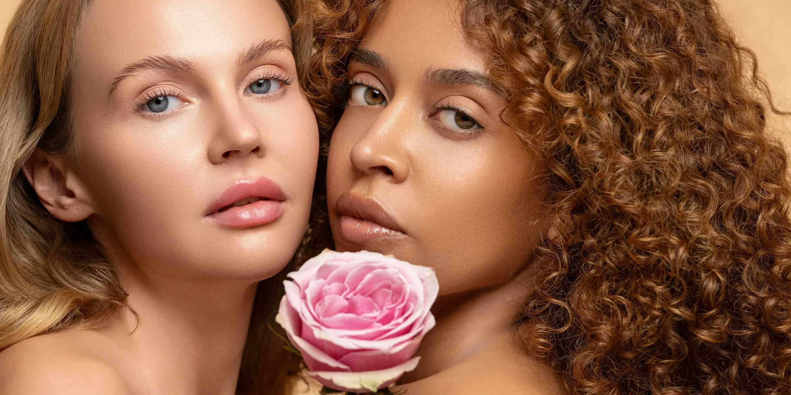 DSC04955 Açık tenli ve esmer makyajlı iki modelin yakın portresi, pembe gülleyle detay odaklı stüdyo kozmetik çekimi.