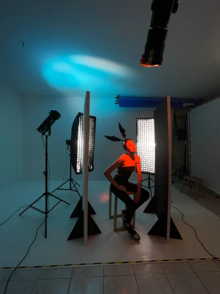 Concept studio shot of a bunny-eared model sitting in the studio with blue backlight and red face accent.