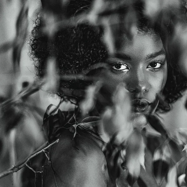 Yapraklar arasından bakışlarıyla öne çıkan siyah beyaz kadın portresi, konsept editorial portre çekimi estetiği taşıyor.