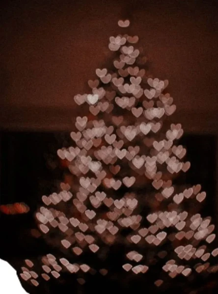 Bulanık arka planda pembe kalp şeklinde ışık bokeh'leriyle süslenmiş Noel ağacı, yaratıcı still life çekimi estetiği taşıyor.